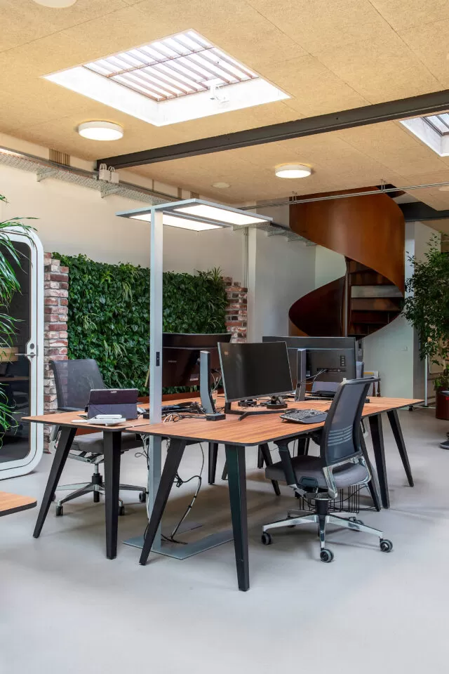Arbeitsplätze mit Wendeltreppe im Hintergrund. Fondation Botnar Basel, Büroeinrichtung von Witzig